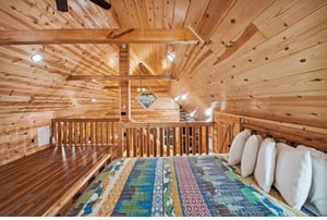Cozy up in your private loft bedroom with rustic wood beams and colorful quilted bedding for mountain cabin charm.
