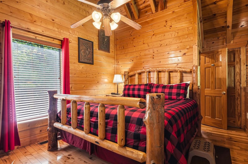Rustic log bed with cozy buffalo plaid bedding invites you to unwind beneath vaulted ceilings and warm wood walls in your mountain retreat.