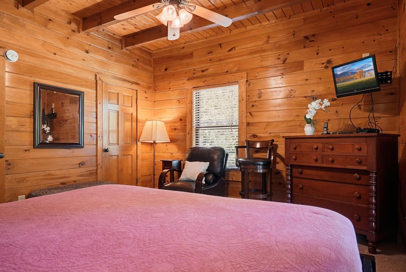 Unwind in your cozy cabin bedroom, where rustic pine walls, a plush bed, and warm lamplight create the perfect mountain retreat after a day of adventure.