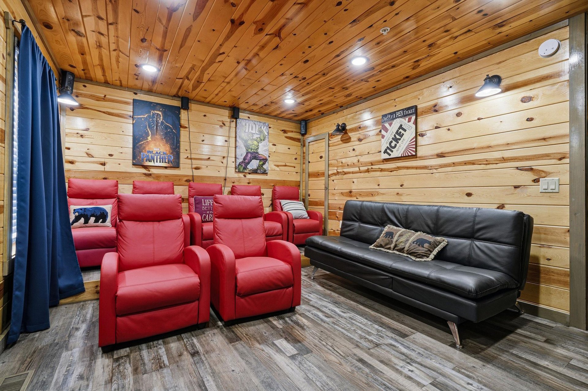 Sink into plush red theater seats and enjoy movie nights in your private cinema room with rustic wood walls and cozy atmosphere.