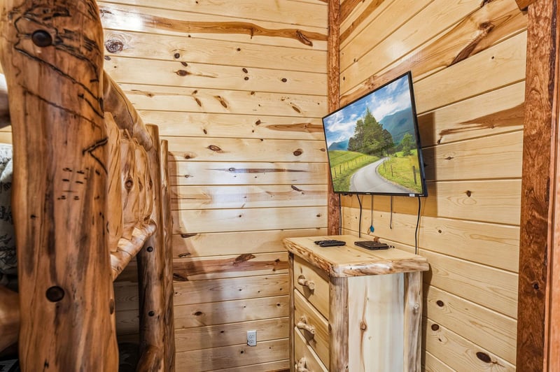 Cozy up in this rustic cabin bedroom featuring handcrafted log furniture and entertainment for your mountain getaway.