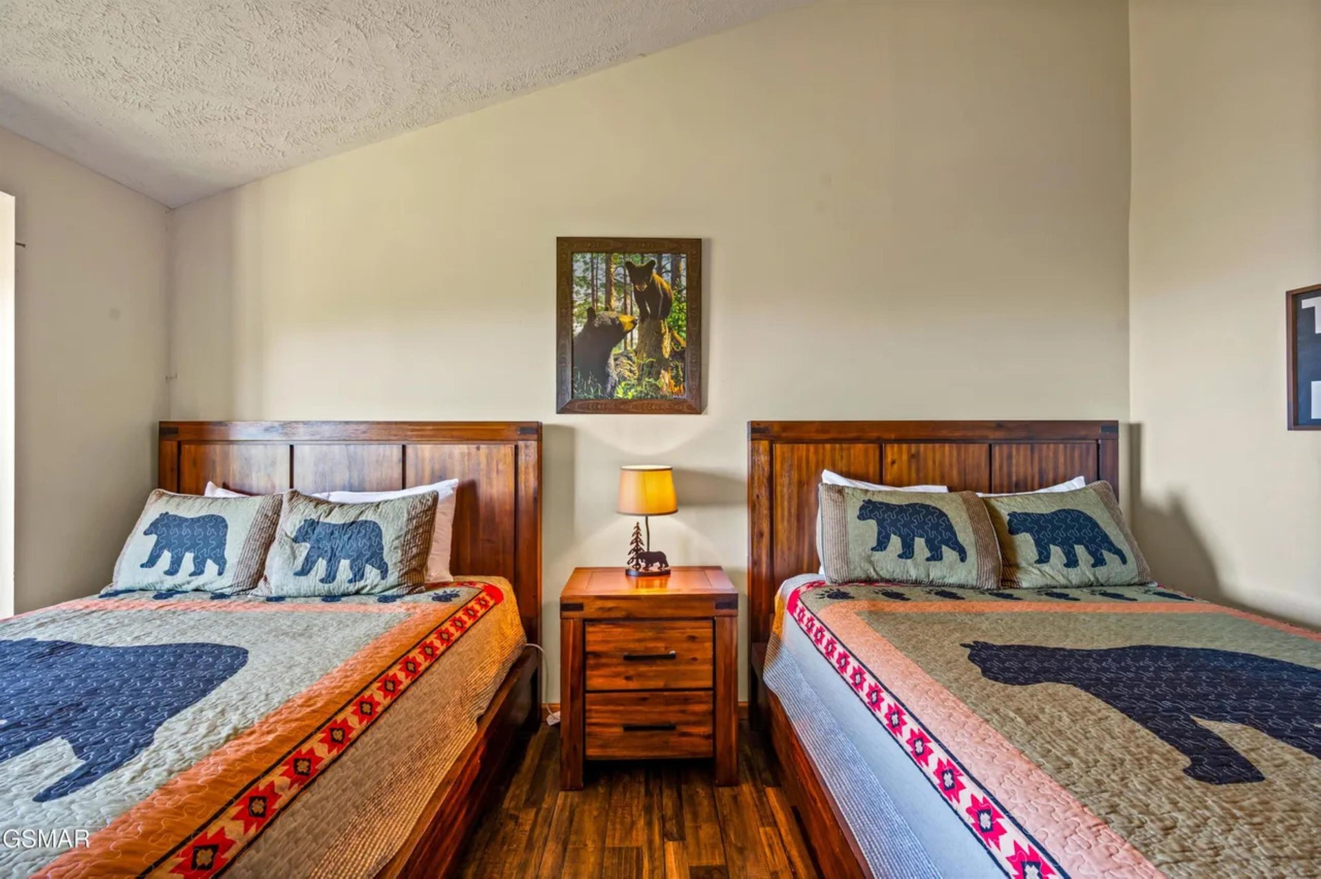 Your rustic retreat features twin beds with charming bearthemed quilts and rich wood furniture creating a cozy mountain cabin atmosphere.