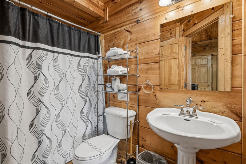 Your private bathroom combines rustic cabin charm with modern comforts, featuring warm wood walls and fresh towels ready for your stay.