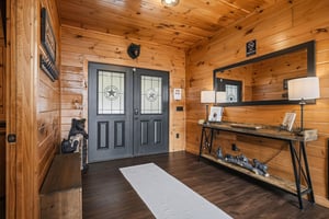 The entrance welcomes you into a warm rustic cabin adorned with knotty pine walls, charming bear decor, and a cozy entryway console for your essentials.