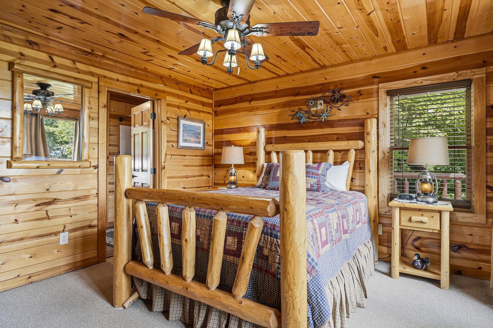 Drift off to sleep in this cozy log bedroom, where rustic charm meets comfort. Natural wood surrounds you, warm lamplight glows beside the bed, and ceiling fans keep you cool.