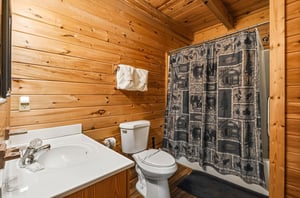 Step into your private rustic bathroom with warm woodpaneled walls, fresh white towels, and a charming cabinstyle shower—a cozy retreat after a day of adventure.