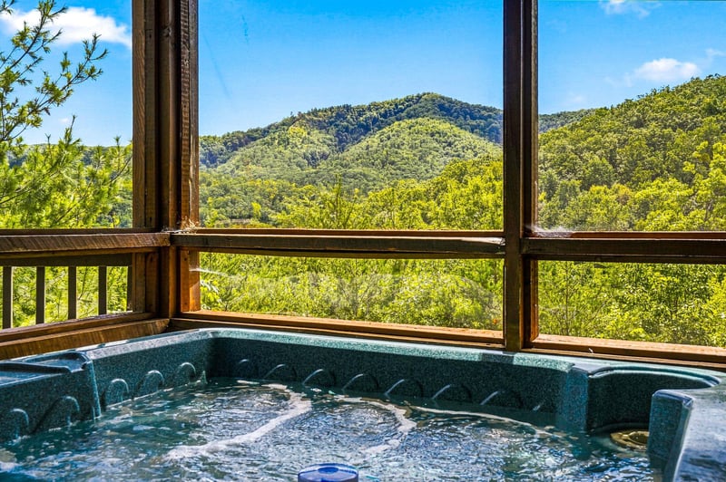 Soak in your private hot tub as you gaze out at rolling mountains and endless green treetops—pure relaxation with natures beauty framing every moment.