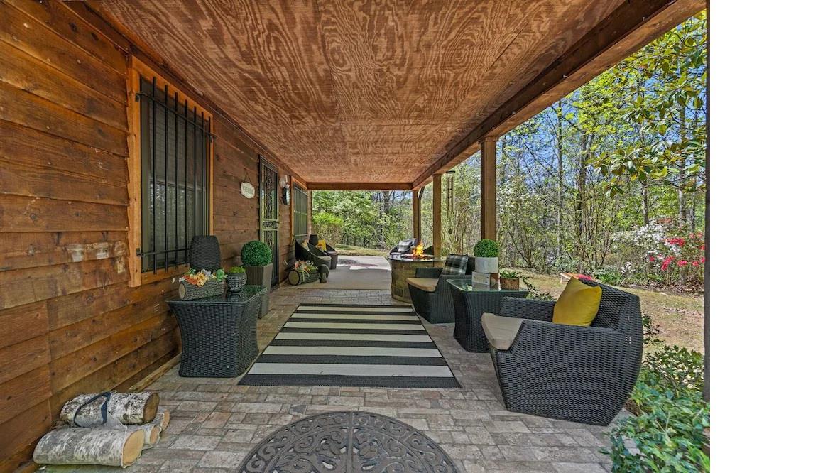 Relax on your covered porch with comfortable seating surrounded by lush gardens and peaceful woodland views.