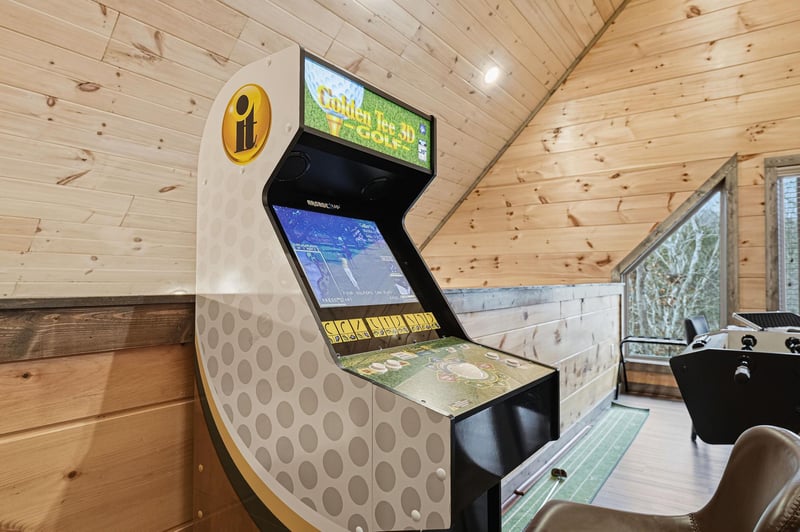 Your own personal game room awaits with a vintage arcade machine ready for hours of nostalgic fun in this cozy woodpaneled space.