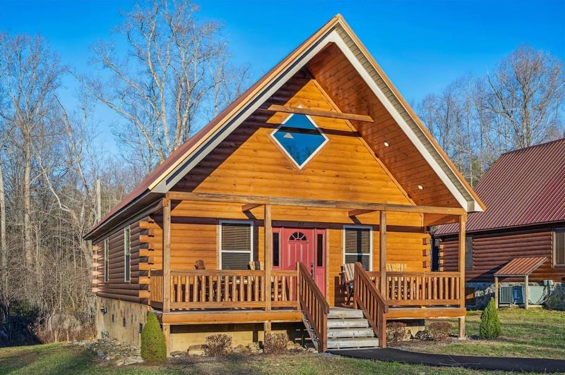 A charming log cabin retreat with rustic wooden siding and welcoming covered porch, perfectly positioned among peaceful wooded surroundings for your mountain getaway.