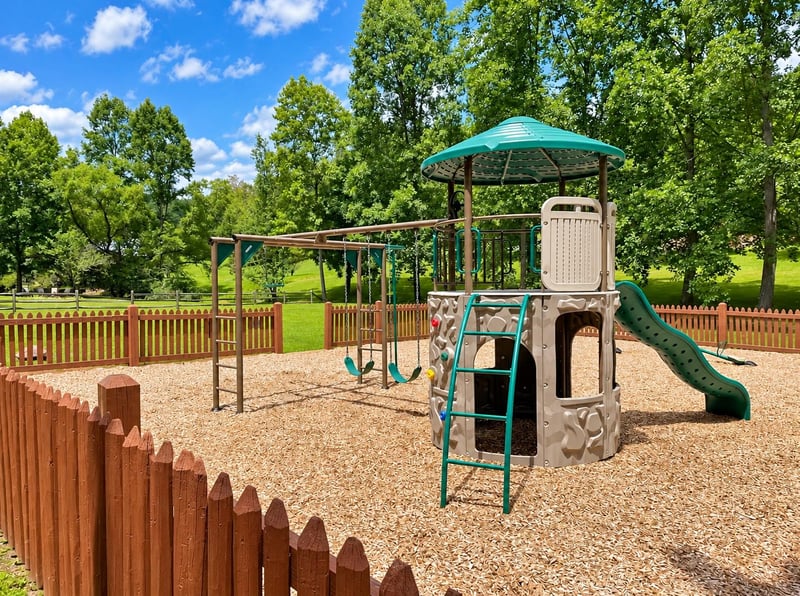 A dedicated childrens playground surrounded by green lawns and mature trees provides a safe outdoor space for families to enjoy sunny days together.