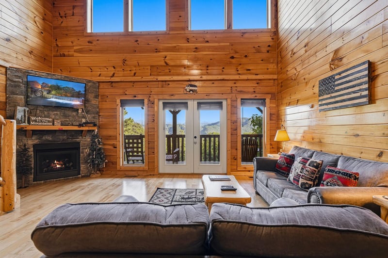 Cozy mountain retreat with soaring windows framing stunning views. Curl up by the stone fireplace and let the warm wood tones wrap you in comfort after exploring the trails.
