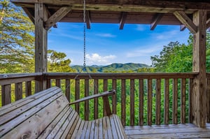 A covered porch with a swing frames stunning mountain views, offering the perfect spot to relax and take in the natural beauty surrounding the property.