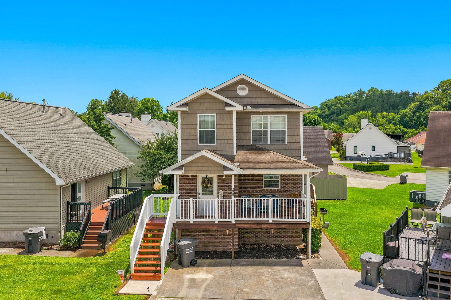 This inviting twostory vacation rental sits in a quiet residential neighborhood, featuring a welcoming front porch, private parking, and lush green surroundings perfect for a relaxing stay.