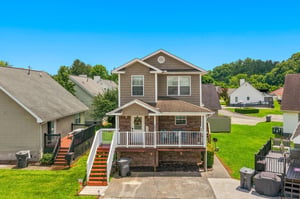 This inviting twostory vacation rental sits in a quiet residential neighborhood, featuring a welcoming front porch, private parking, and lush green surroundings perfect for a relaxing stay.