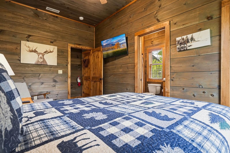Sink into the comfort of your rustic mountain bedroom, where warm wood walls, soft quilts, and charming wildlife art create a cozy retreat after a day of adventure.