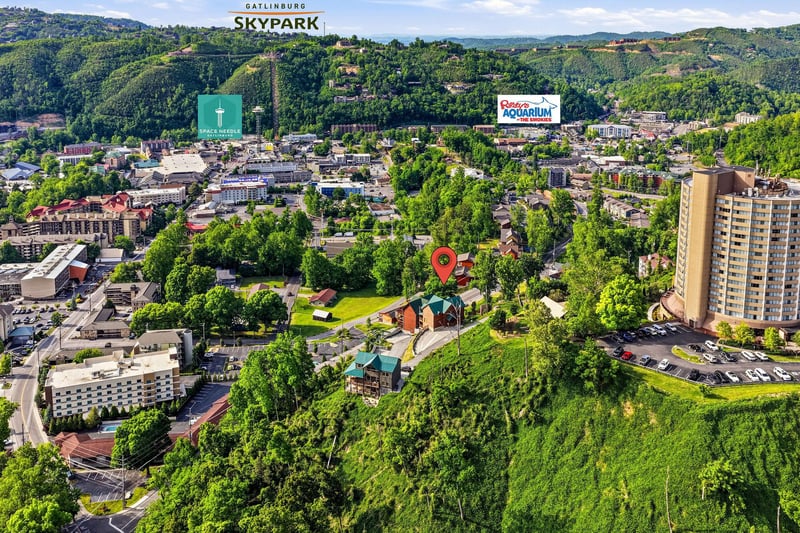 An aerial view of Gatlinburg showcasing the propertys prime location amidst lush green hills and nearby attractions including SkyPark, the Space Needle, and Ripleys Aquarium.