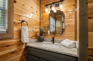 Step into your rustic bathroom where warm cedar walls and granite counters create a cozy cabin retreat.