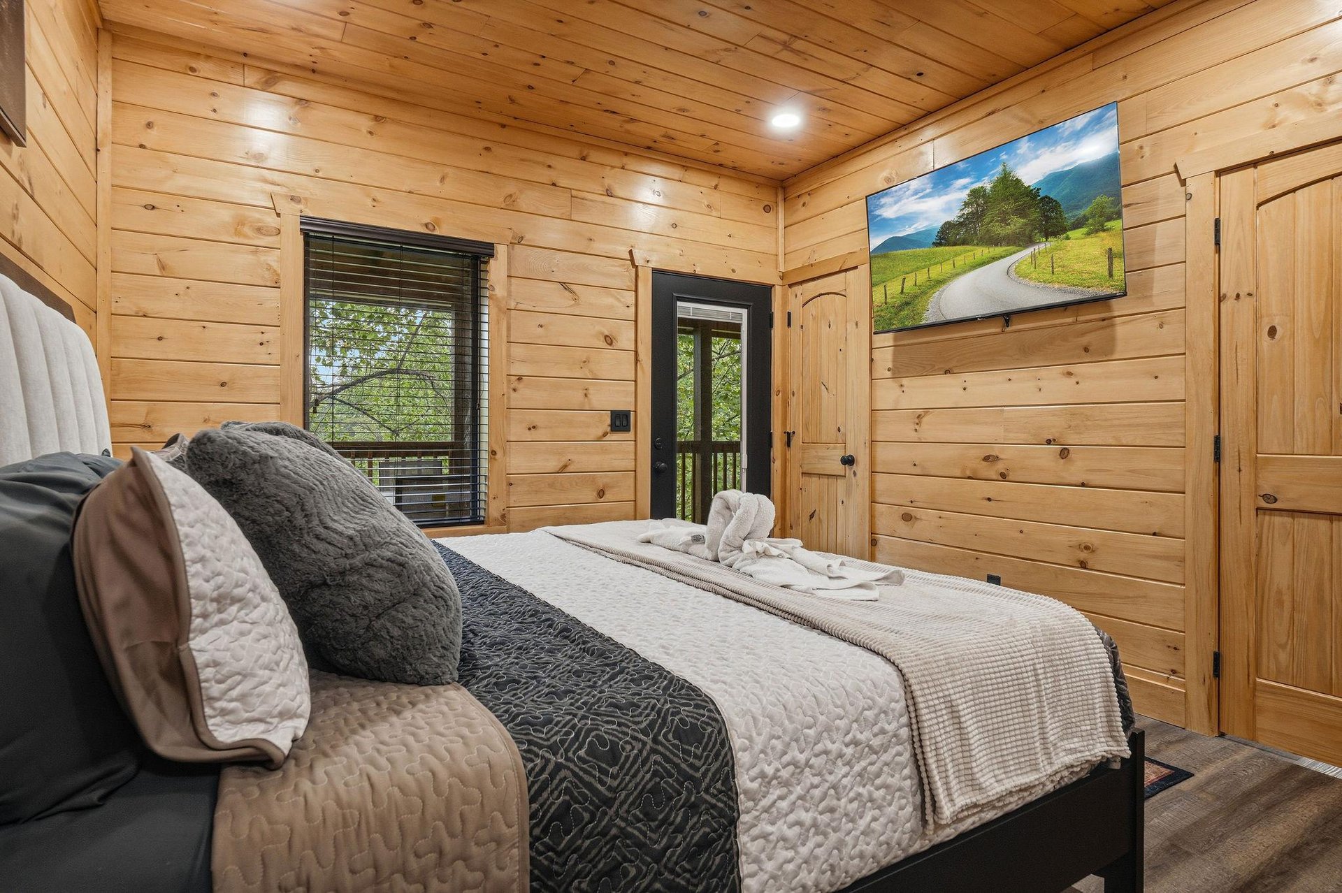 Cozy wooden bedroom with plush bedding and forest views through your window for peaceful mountain cabin vibes.