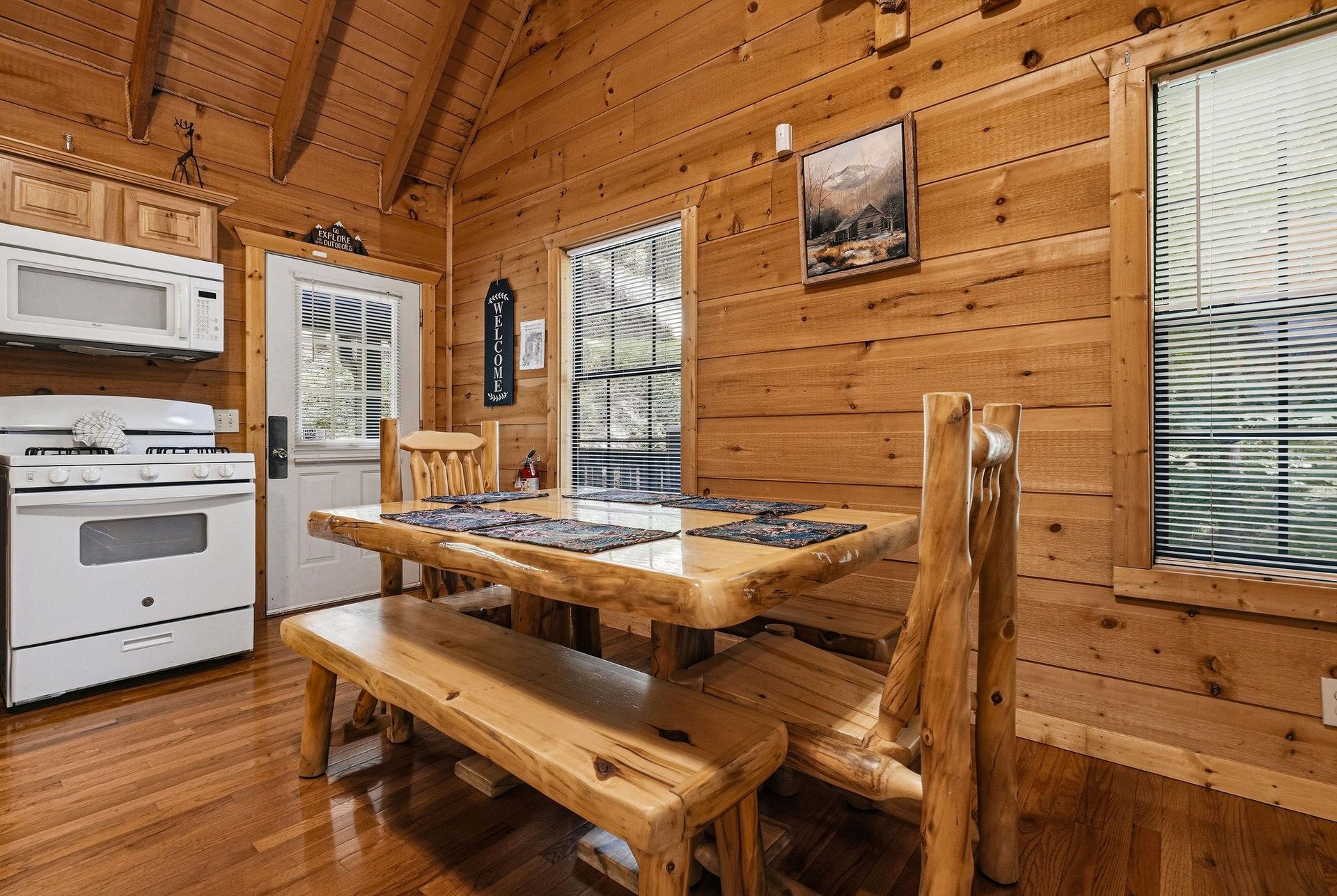 Gather around the rustic log dining table in your cozy cabin retreat, where warm wood surroundings and mountain views create the perfect setting for memorable meals together.