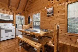 Gather around the rustic log dining table in your cozy cabin retreat, where warm wood surroundings and mountain views create the perfect setting for memorable meals together.