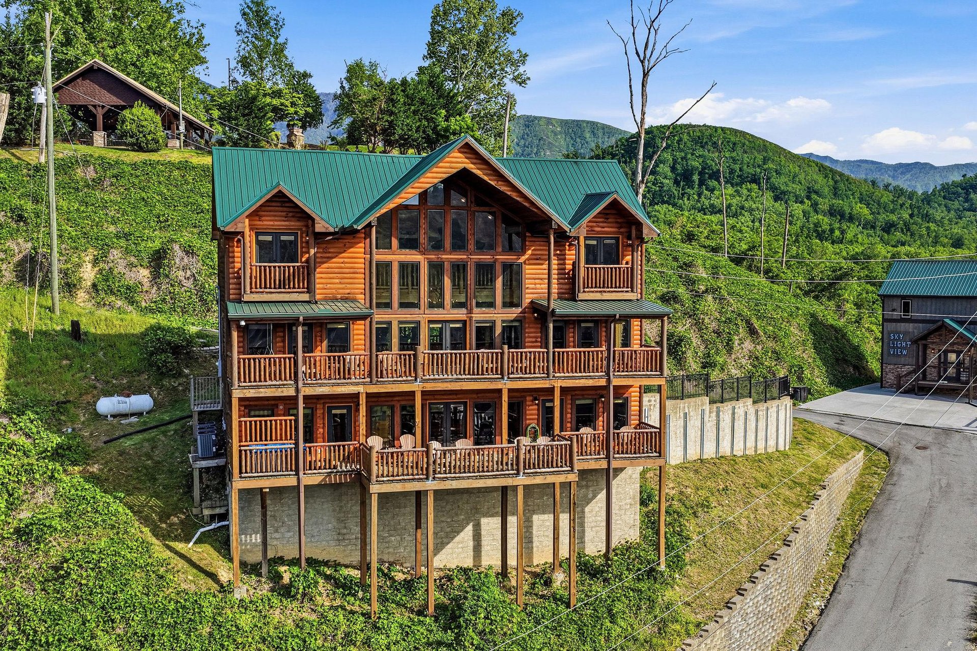 This multistory log cabin rental sits nestled in the lush mountain landscape, offering expansive balconies and large windows to frame the stunning forested peaks surrounding the property.