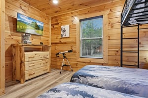 Drift off in your cozy cabin bedroom, where warm wood walls meet modern comforts. Gaze at starry skies through the telescope, or catch your favorite shows on the flatscreen before climbing to the top