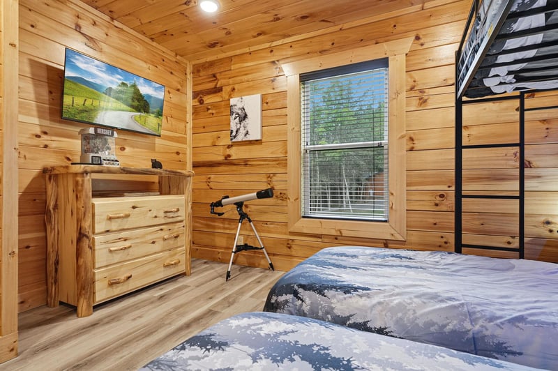 Drift off in your cozy cabin bedroom, where warm wood walls meet modern comforts. Gaze at starry skies through the telescope, or catch your favorite shows on the flatscreen before climbing to the top