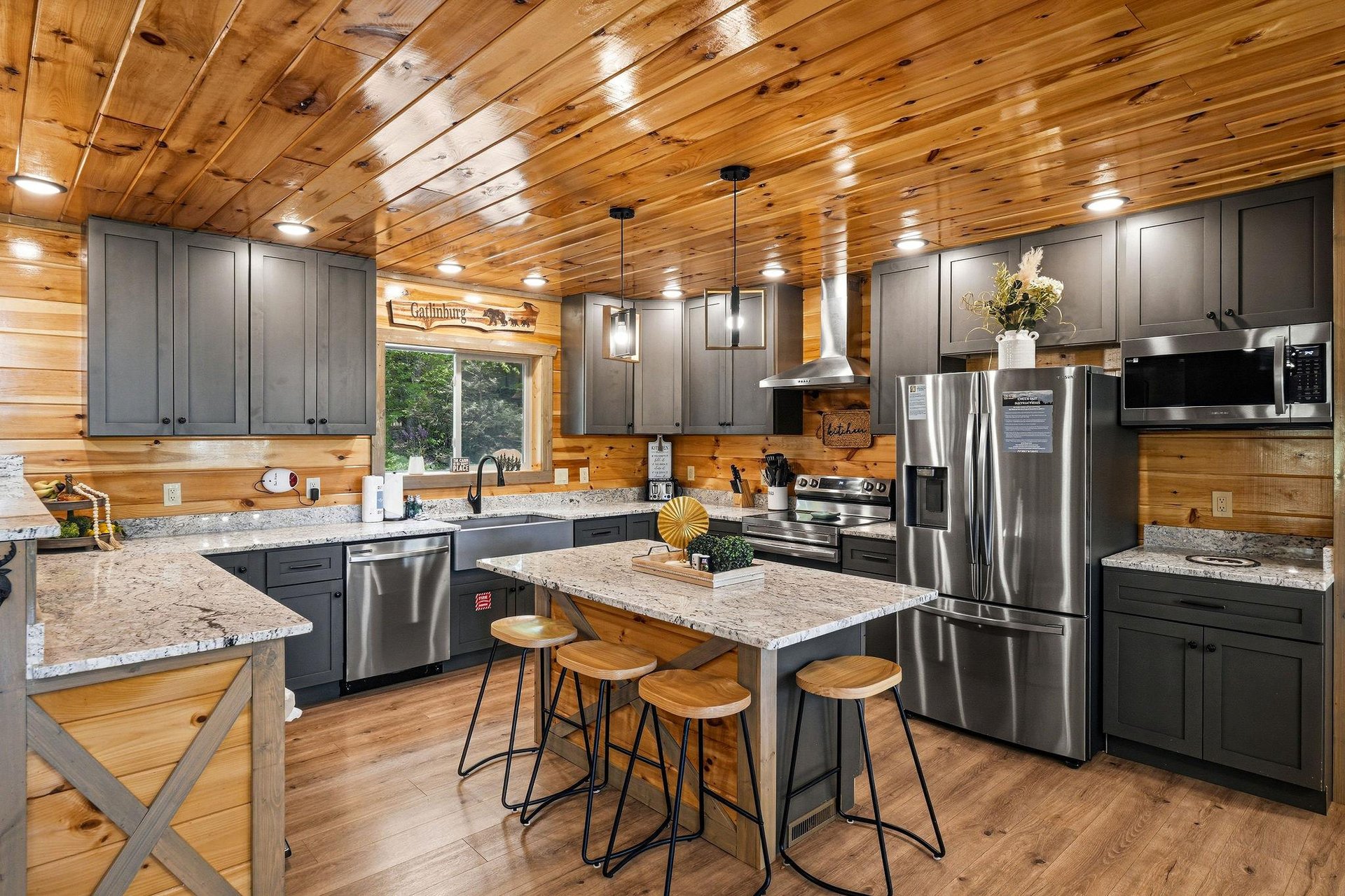 Youll love cooking in this stunning rustic kitchen with modern stainless steel appliances and granite countertops beneath warm wood ceilings.