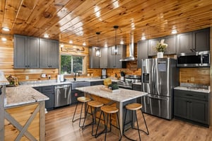 Youll love cooking in this stunning rustic kitchen with modern stainless steel appliances and granite countertops beneath warm wood ceilings.