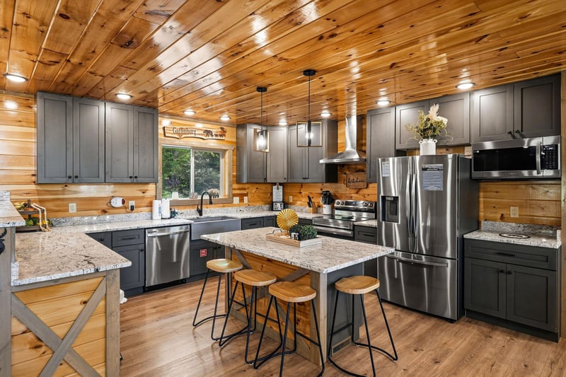 Youll love cooking in this stunning rustic kitchen with modern stainless steel appliances and granite countertops beneath warm wood ceilings.