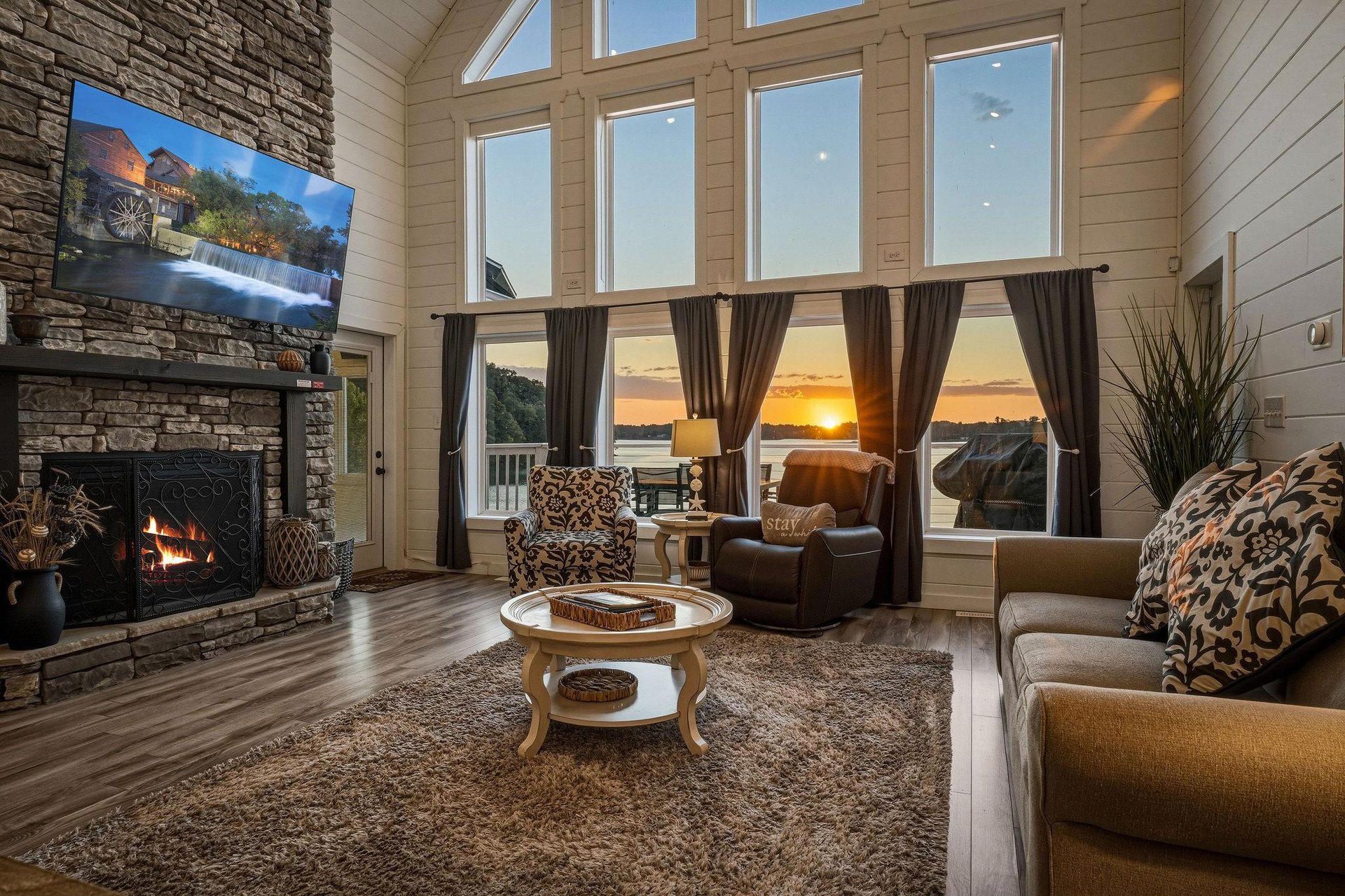 Sink into plush seating as the fireplace warms your evening and a stunning waterfront sunset paints the sky beyond floortoceiling windows, creating an unforgettable retreat.