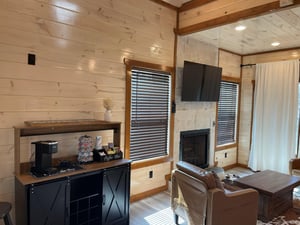 Relax in your cozy living space with rustic wood walls, crackling fireplace, and modern amenities like coffee station and flatscreen TV.