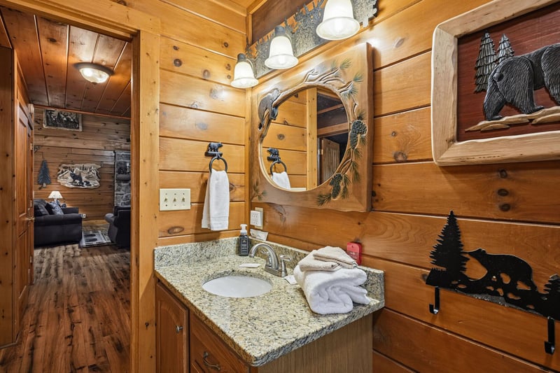 Your private bathroom blends rustic cabin charm with thoughtful touches, featuring warm wood walls, natureinspired decor, and plush towels ready for your mountain getaway.
