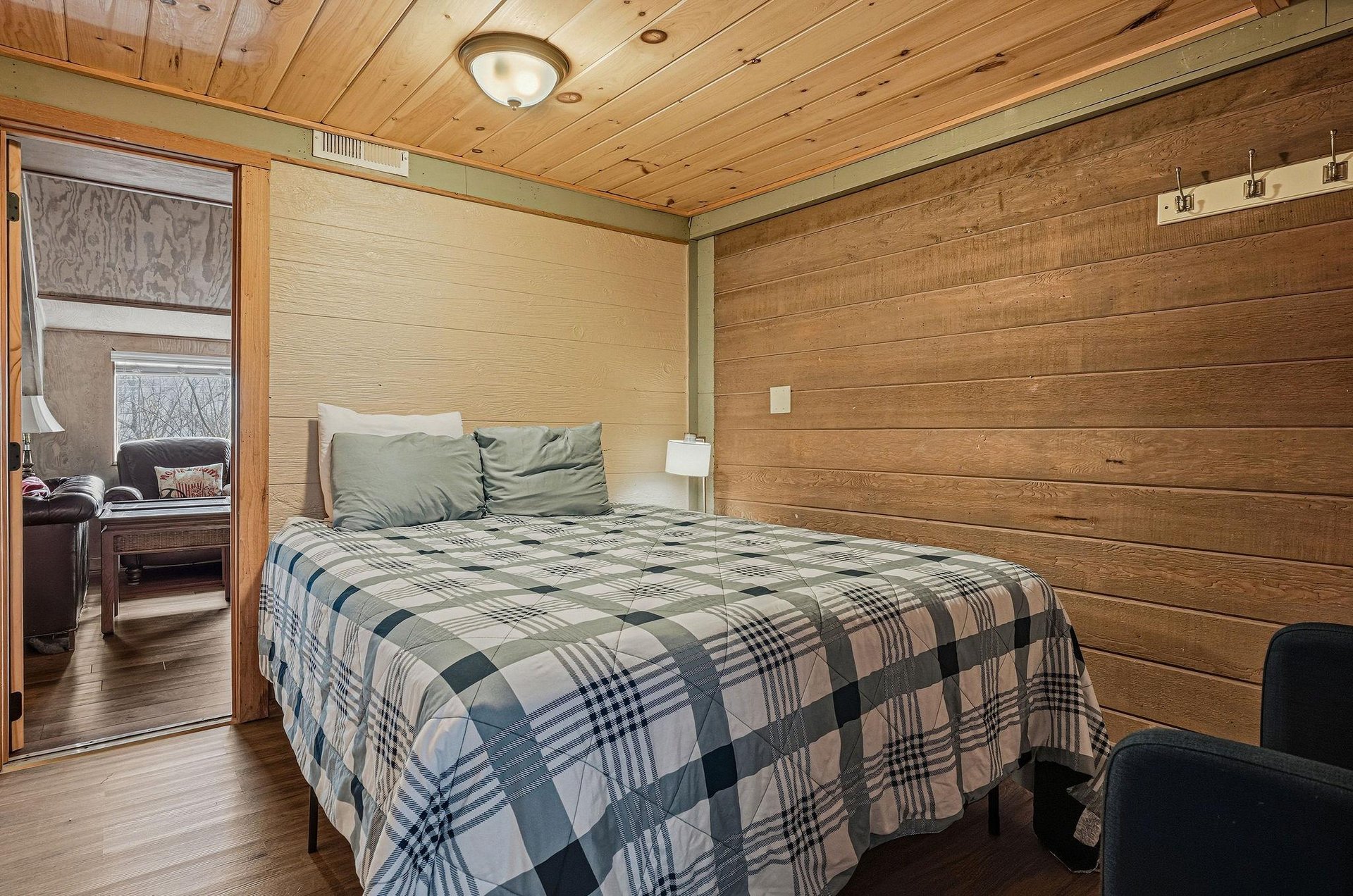 Cozy cabin bedroom with rustic wood walls where youll sleep peacefully under soft plaid bedding.