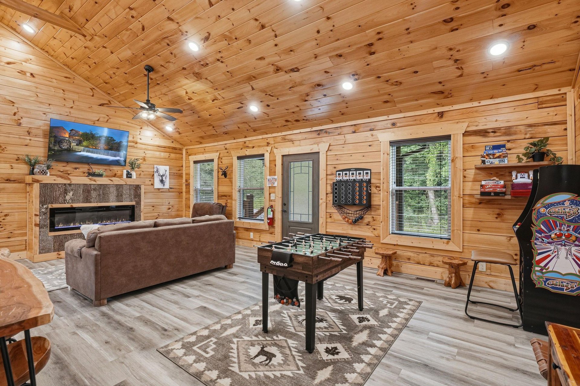 Your cozy cabin retreat features warm wood interiors, a gas fireplace, foosball table, and arcade game—perfect for unwinding after exploring nearby trails.