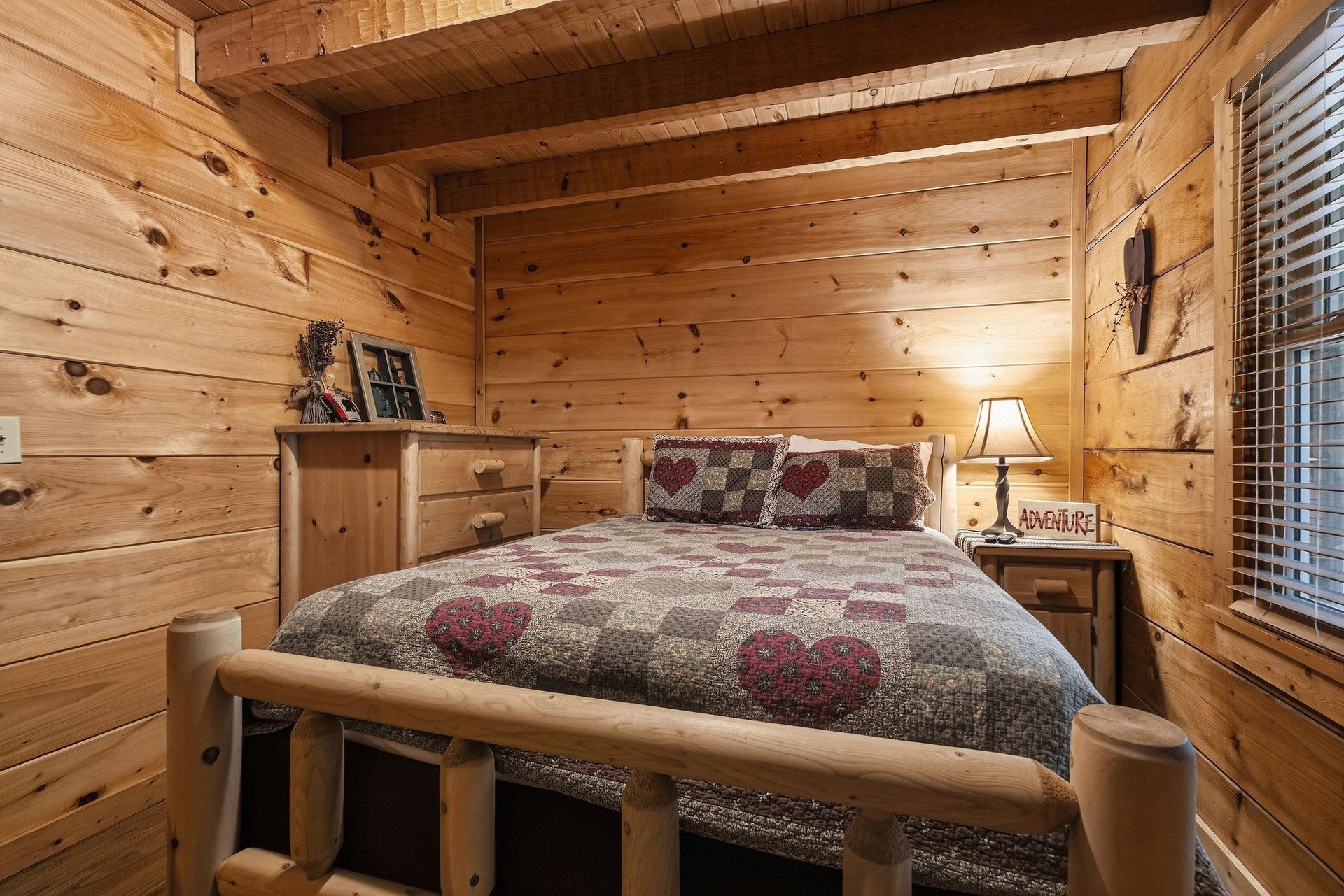 Drift off to sleep surrounded by warm pine walls and rustic log furniture. The vaulted ceiling and cozy heartpatterned bedding create your perfect mountain retreat.