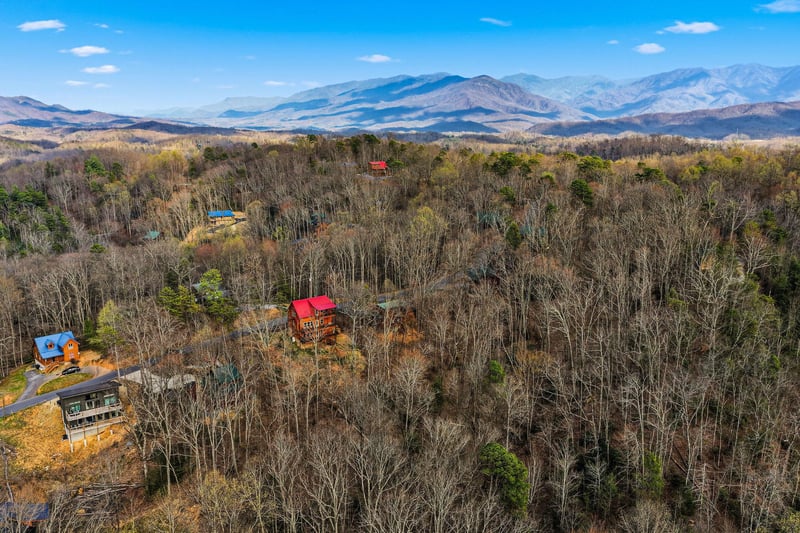Aerial view showcasing mountain cabins nestled in forested landscape with stunning Blue Ridge Mountain backdrop.