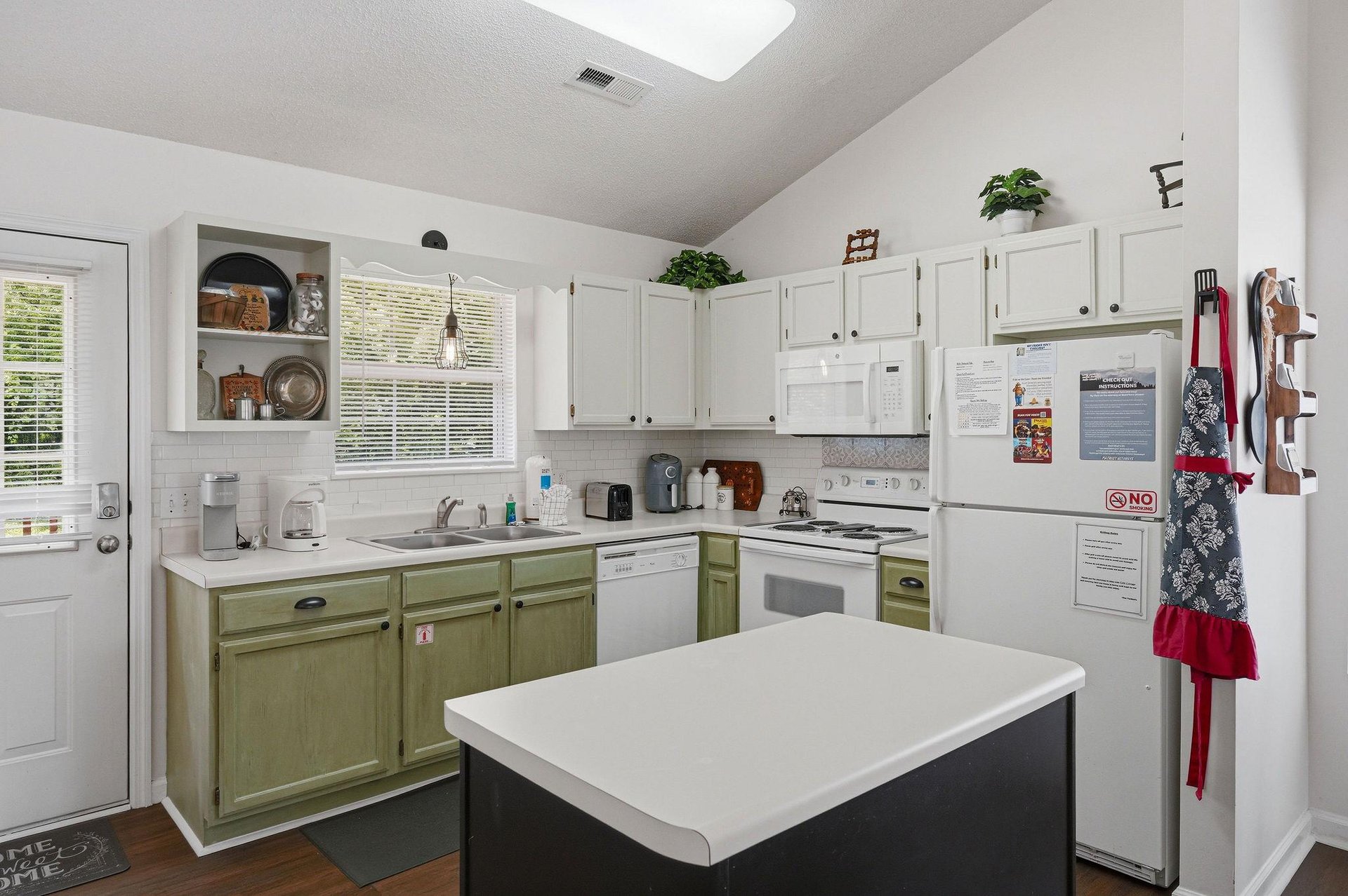Picture yourself cooking your favorite meal in this bright, welcoming kitchen—fresh plants on the cabinets, plenty of counter space, and a charming twotone design that makes every culinary moment fee