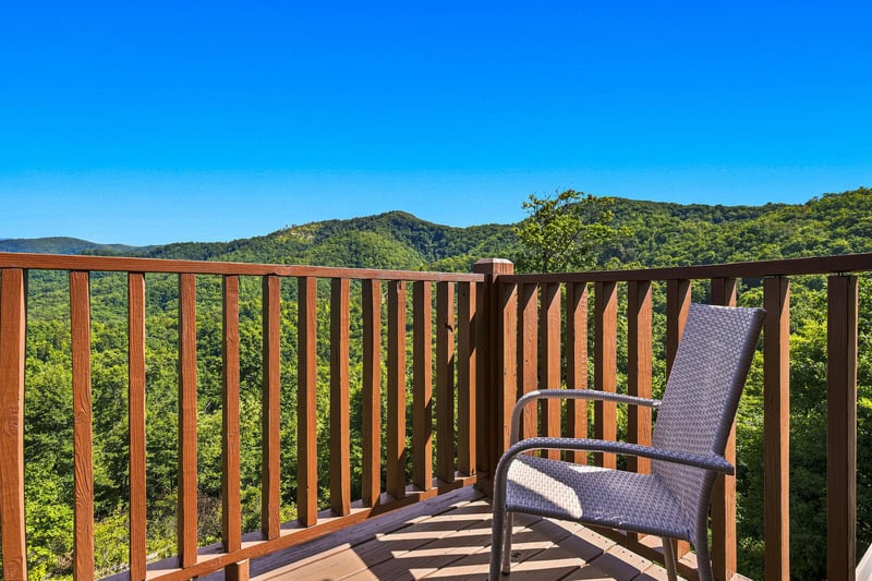 Sweeping mountain ridges stretch across the horizon from this elevated vantage point. Lush green forests blanket the landscape below, framing this tranquil outdoor viewing area. Perfect spot for morni