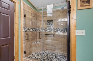 Step into your spacious walkin shower, where woodlook tiles and river rock details create a soothing, spalike retreat after a day of adventure.