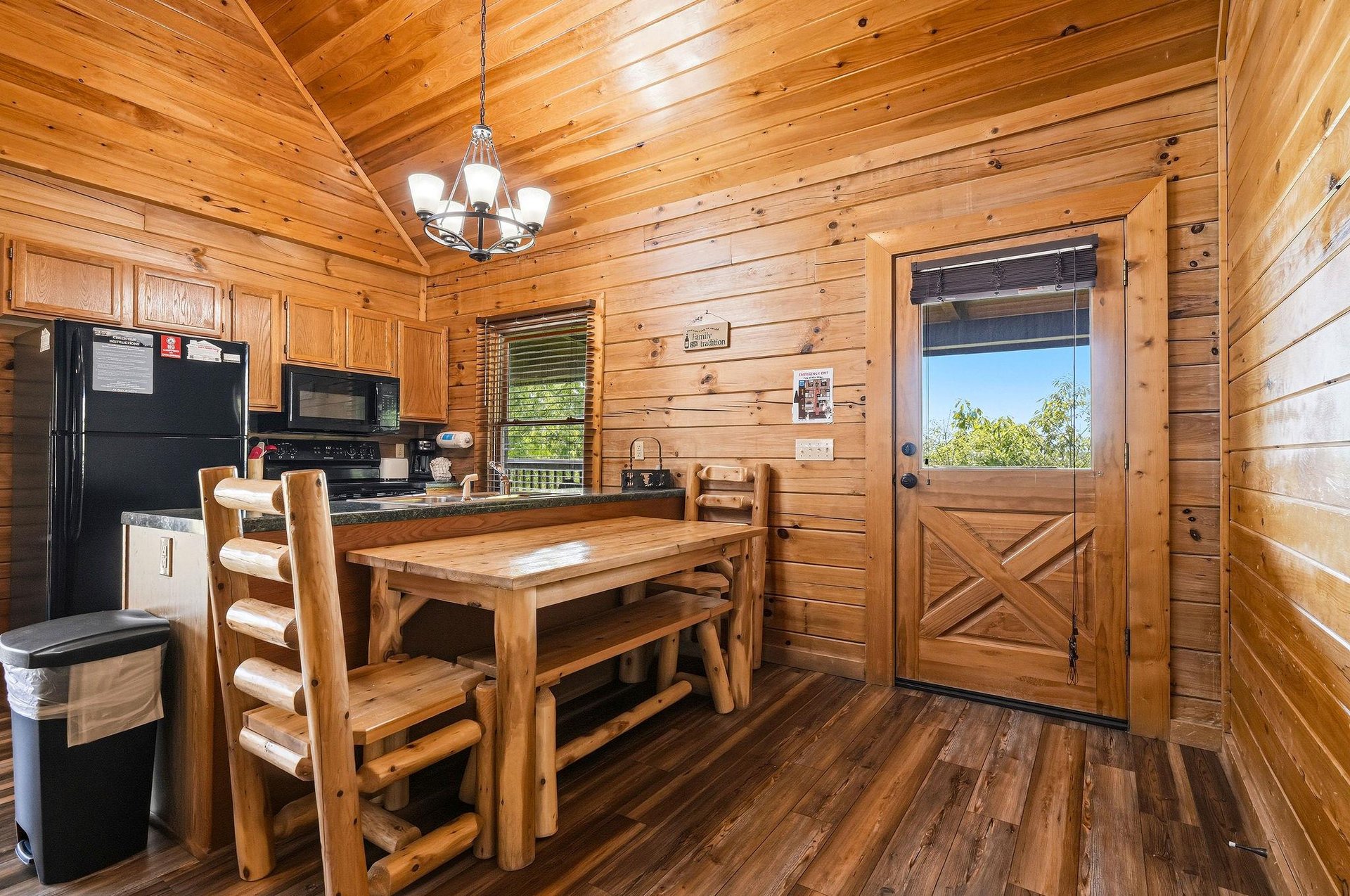 Step into your cozy cabin retreat with rich wood paneling and vaulted ceilings. Sunlight streams through, highlighting the inviting dining space and fullyequipped kitchen—your perfect home base.