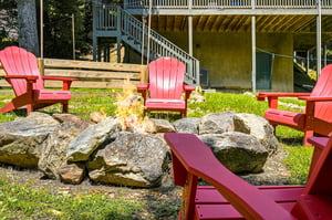 Picture yourself gathered around this rustic fire pit in vibrant Adirondack chairs, sharing stories under open sky. A perfect spot for your evening winddown.