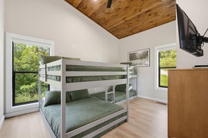 Your family can unwind in this cozy bunk room, where warm wood ceilings and leafy views create a peaceful retreat for restful nights and lazy mornings.