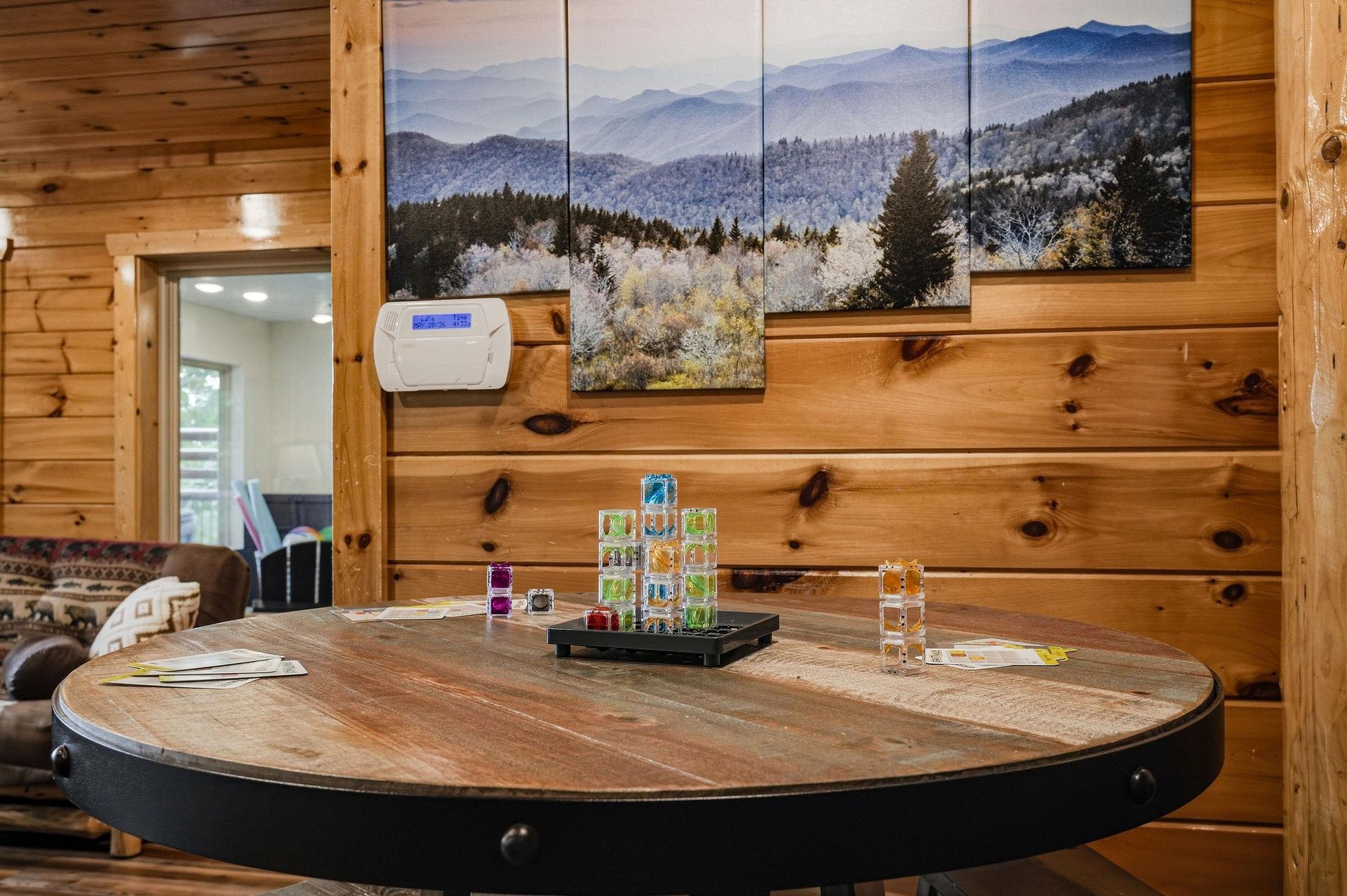 Gather around this rustic table for game nights or morning coffee, with mountain views and cozy wood walls framing your cabin escape.