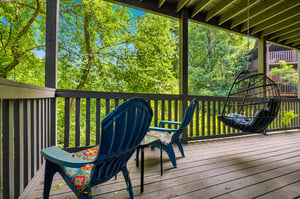 Settle into your private balcony with lush forest views framing every moment. Vibrant cushions and a cozy hanging chair invite you to unwind outdoors in serene natural beauty.