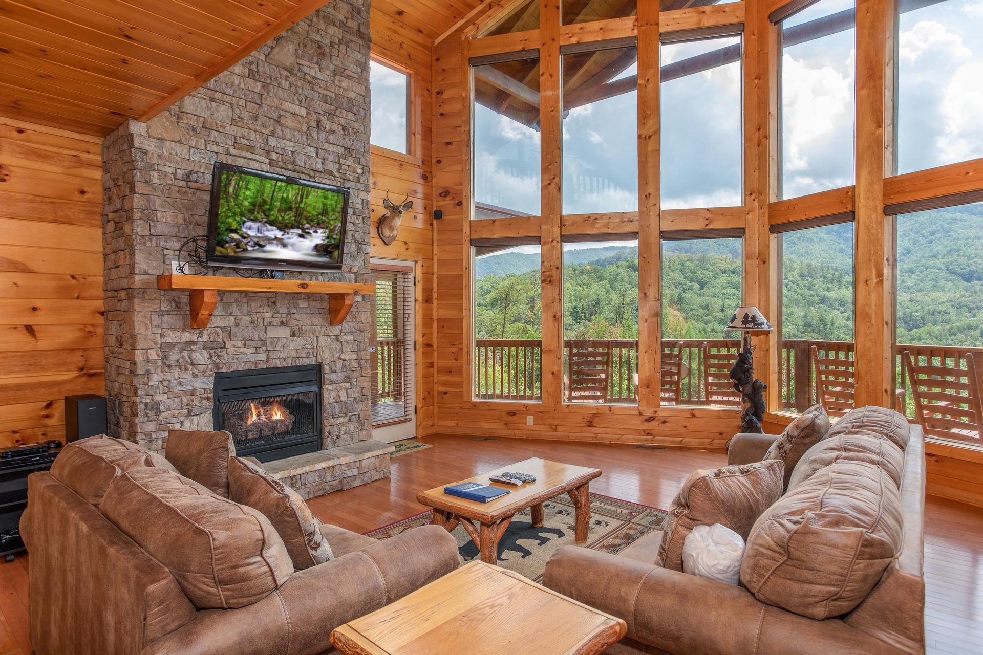 Vaulted ceilings with floortoceiling windows, fireplace, and TV at Four Seasons Lodge, a 3bedroom cabin rental located in Pigeon Forge