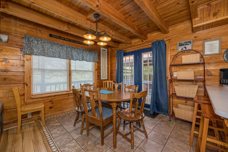 Gather around this warm wooden dining table where meals become memories in your cozy log cabin retreat.