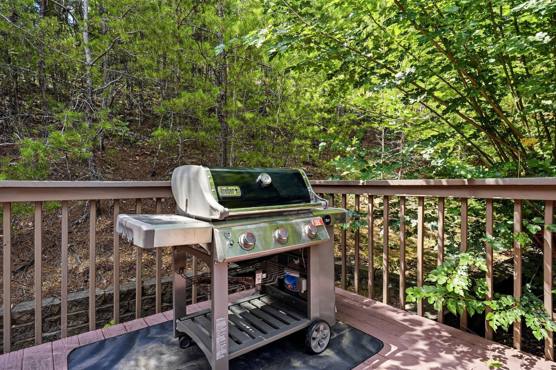 Fire up the grill on your private deck, surrounded by lush forest views and dappled sunlight filtering through the trees—your perfect spot for outdoor cooking.