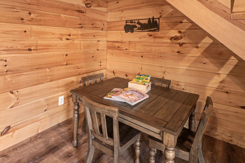 Your cozy reading nook awaits with rustic wooden table perfect for morning coffee and games under slanted ceilings.